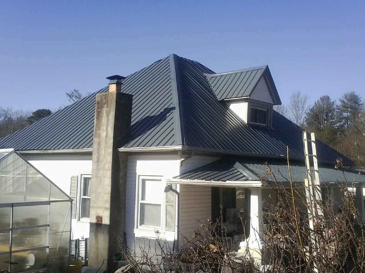 Dark blue standing seam metal roof on a white farmhouse with dormer — Slate & Tile Roof Repair by Roofing Brothers in Mars Hill