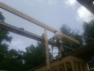 Carpenter setting a ridge beam over a new addition frame — Ice Dam Removal by Roofing Brothers in Mars Hill