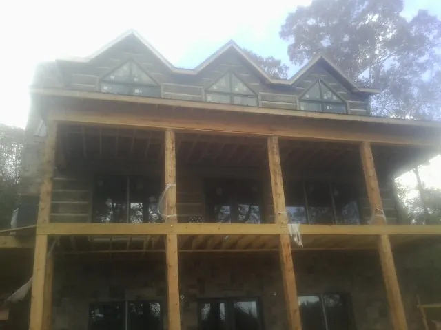 Dormers and porch framing on a large log home under construction — Roof Coating work by our crew in Mars Hill