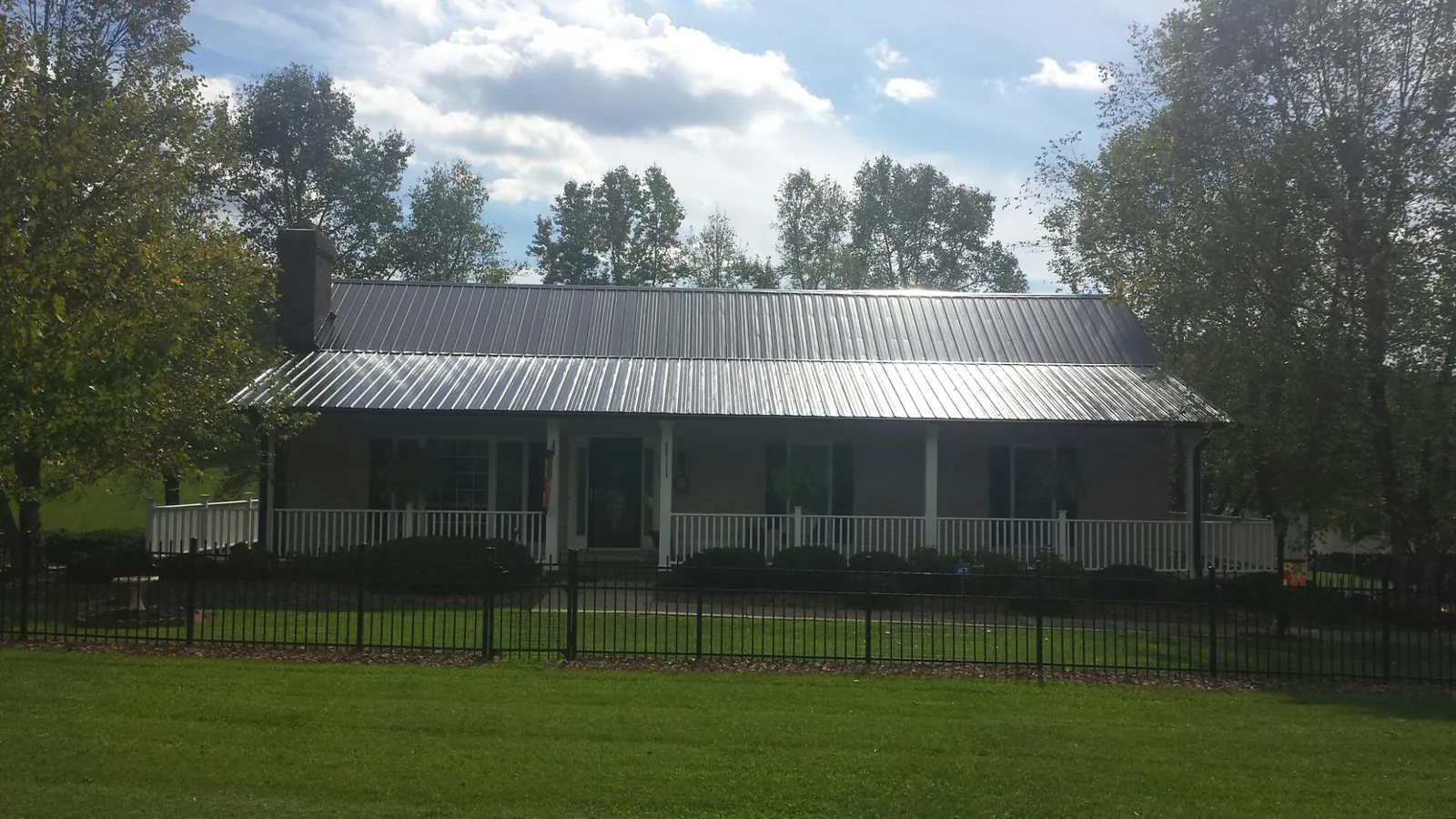 Gray metal roof on a brick ranch with a full width front porch — Gutter Guard Installation work by our crew in Mars Hill