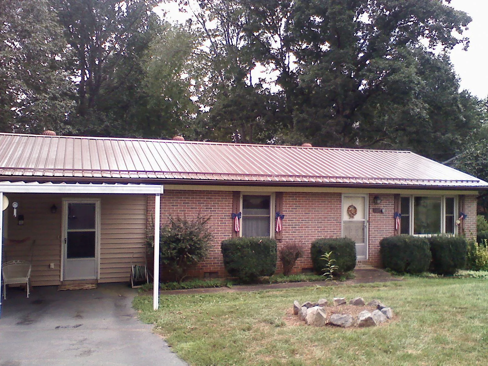 Bronze metal roof and carport on a brick ranch home — Roof Repair work by our crew in Mars Hill