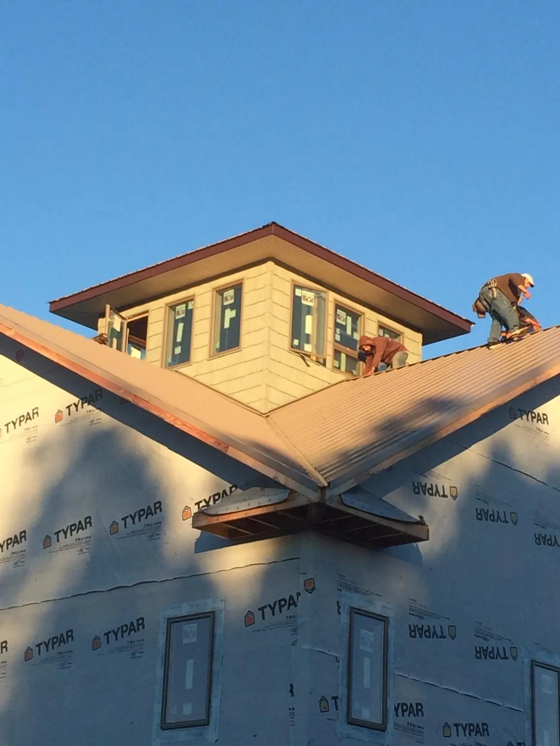 Roofers working around a rooftop cupola on a new metal roof at sunset — Roof Waterproofing in Mars Hill by Roofing Brothers